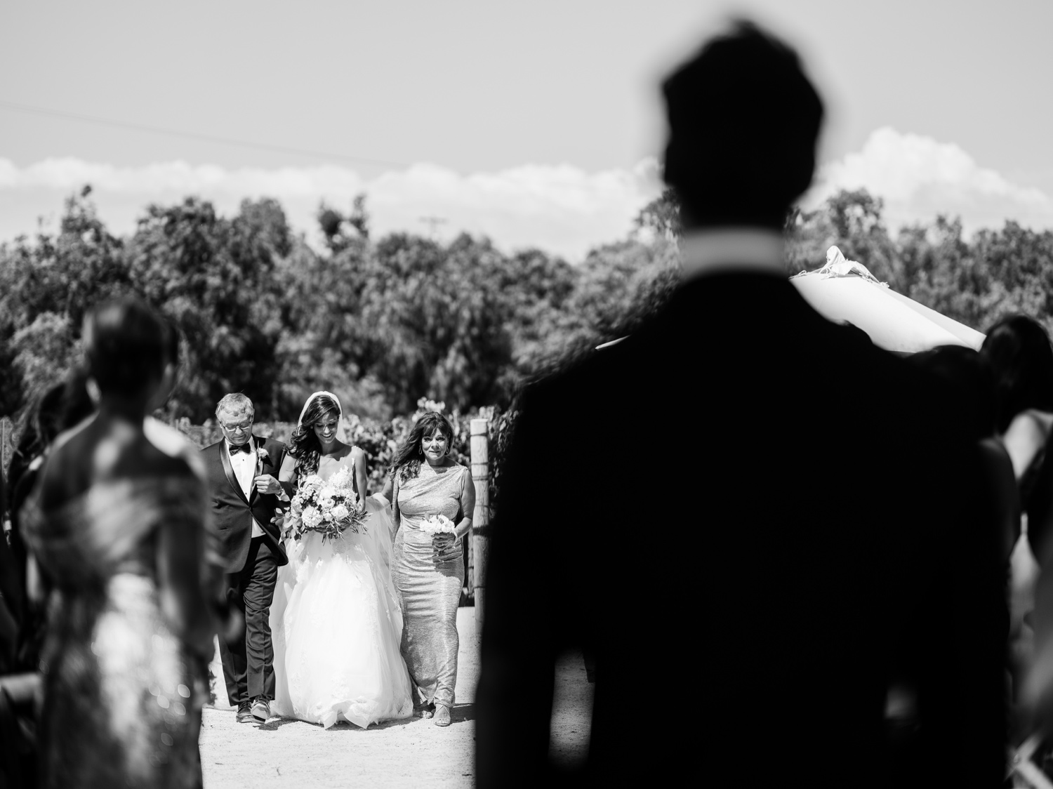 Black and white photo of groom watching his bride walk down the aisle