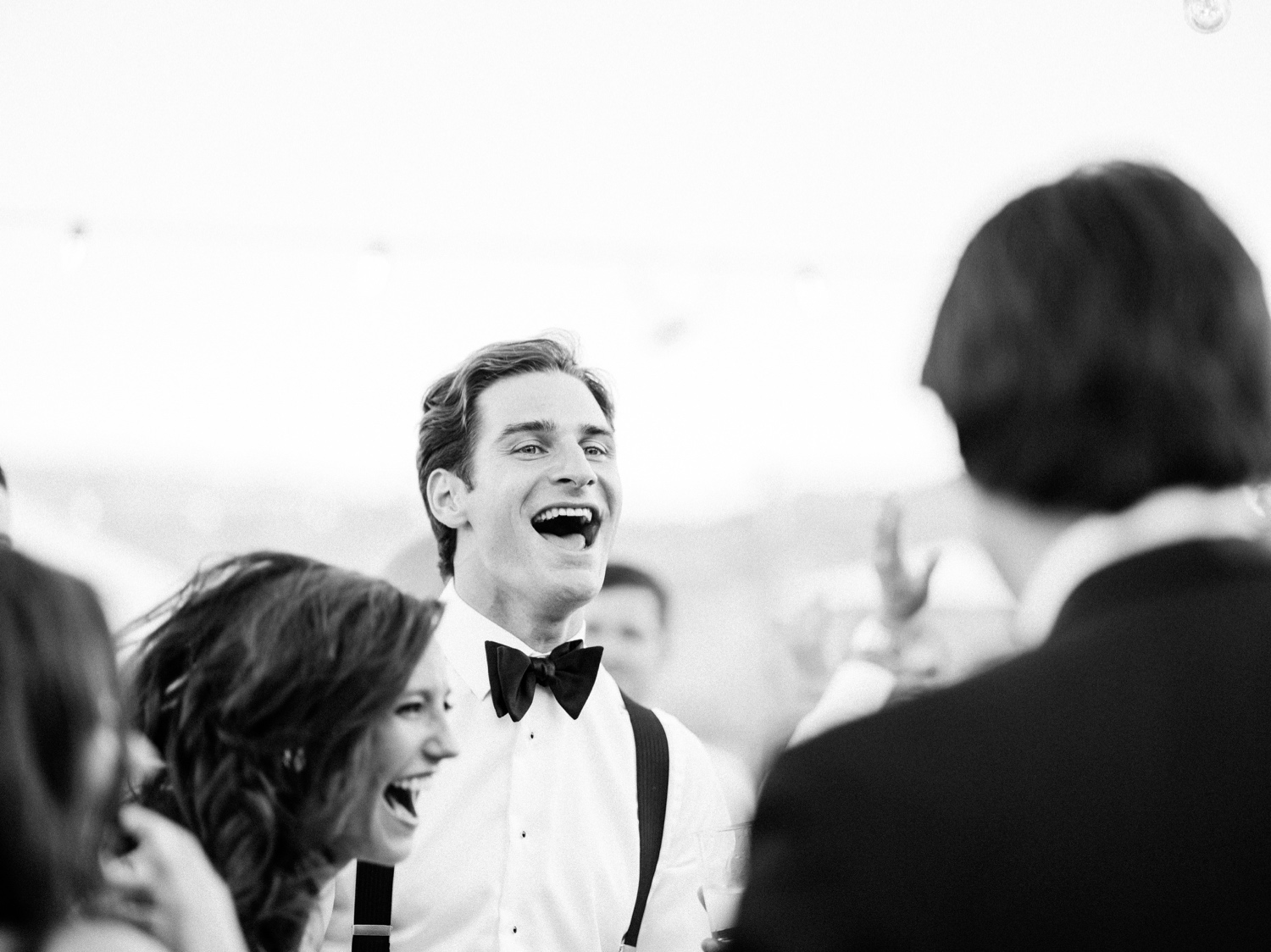 Black and white wedding photo of bride and groom laughing during reception