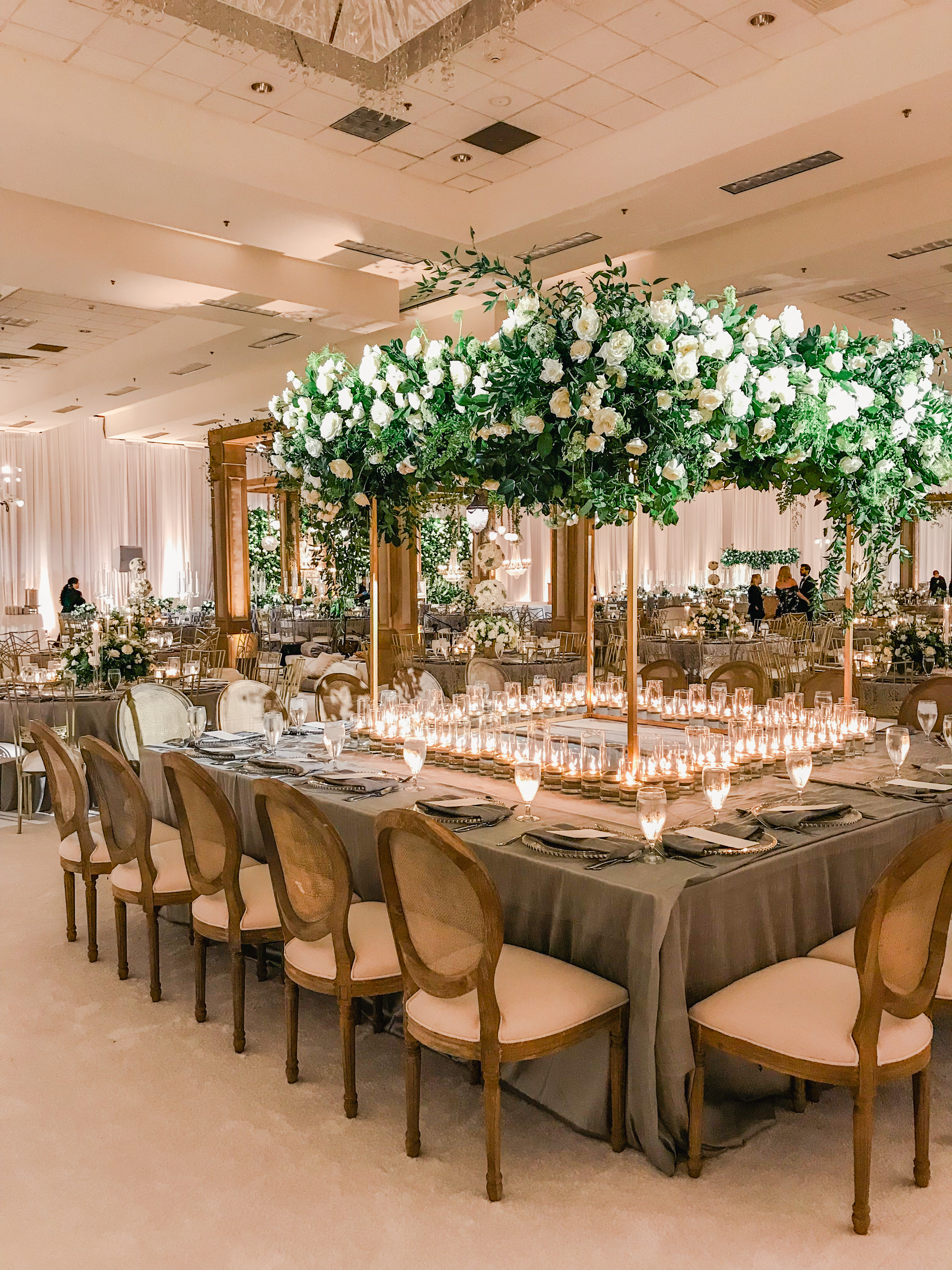 Photo of square table set up with large white rose arrangement over table setting