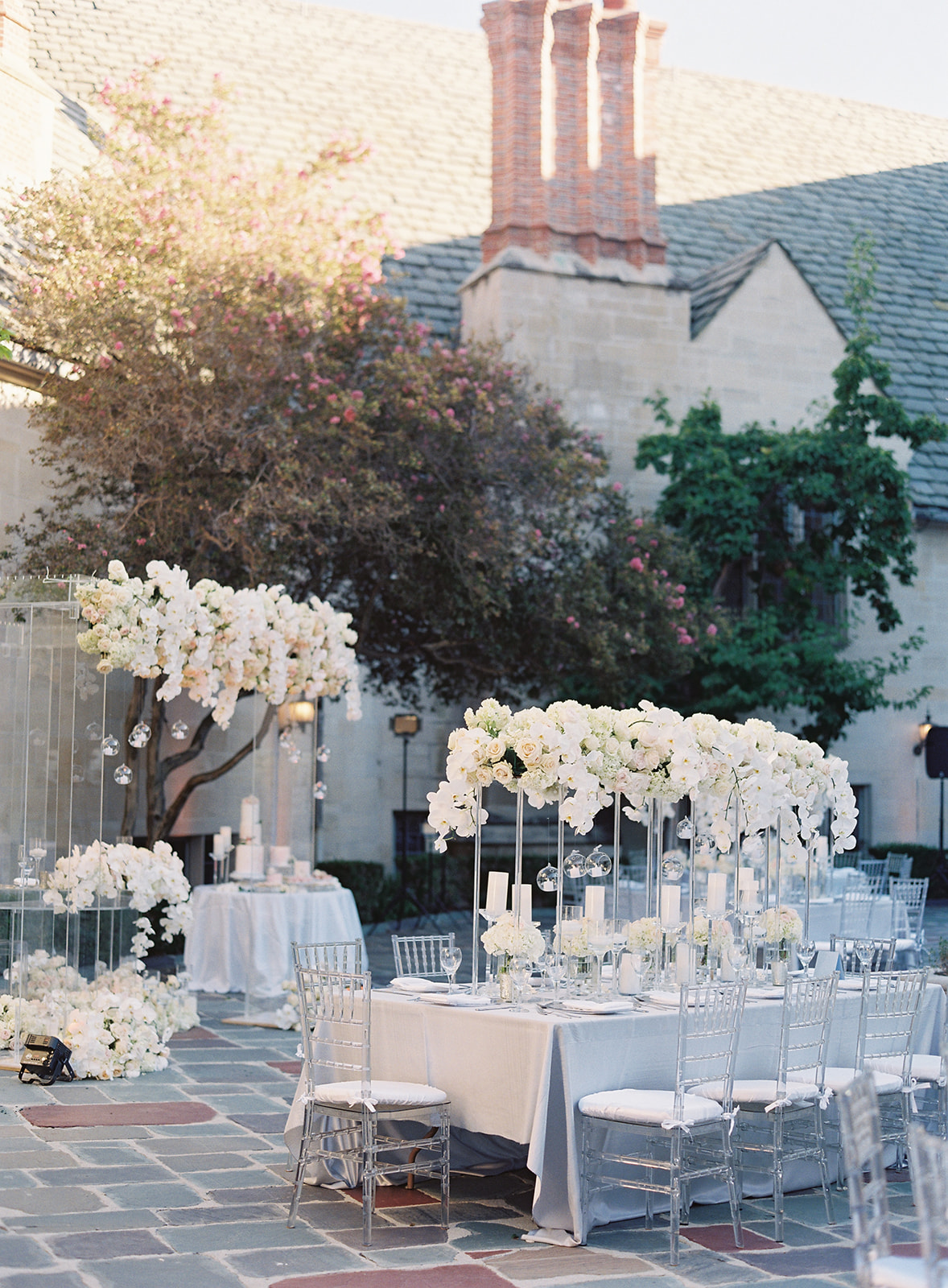 Photo of reception tables with clear chairs and floral centerpieces cascading down towards tables