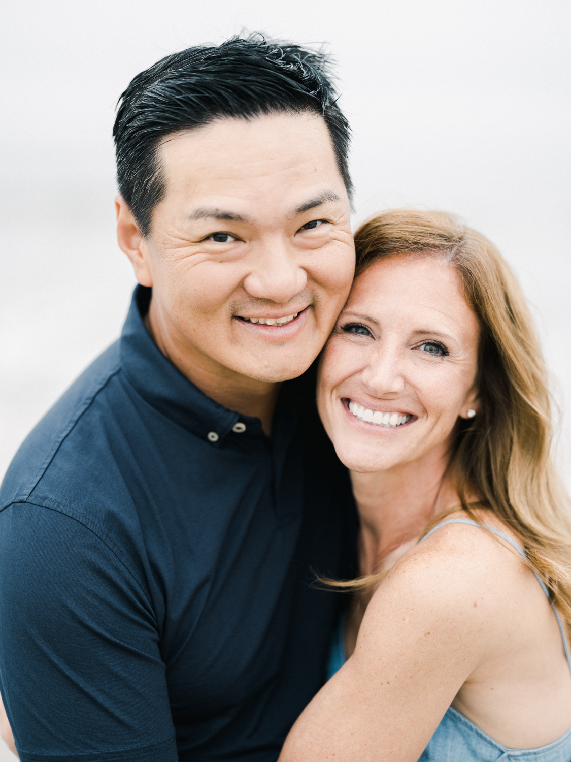 Couple holding one another at the beach and looking into camera