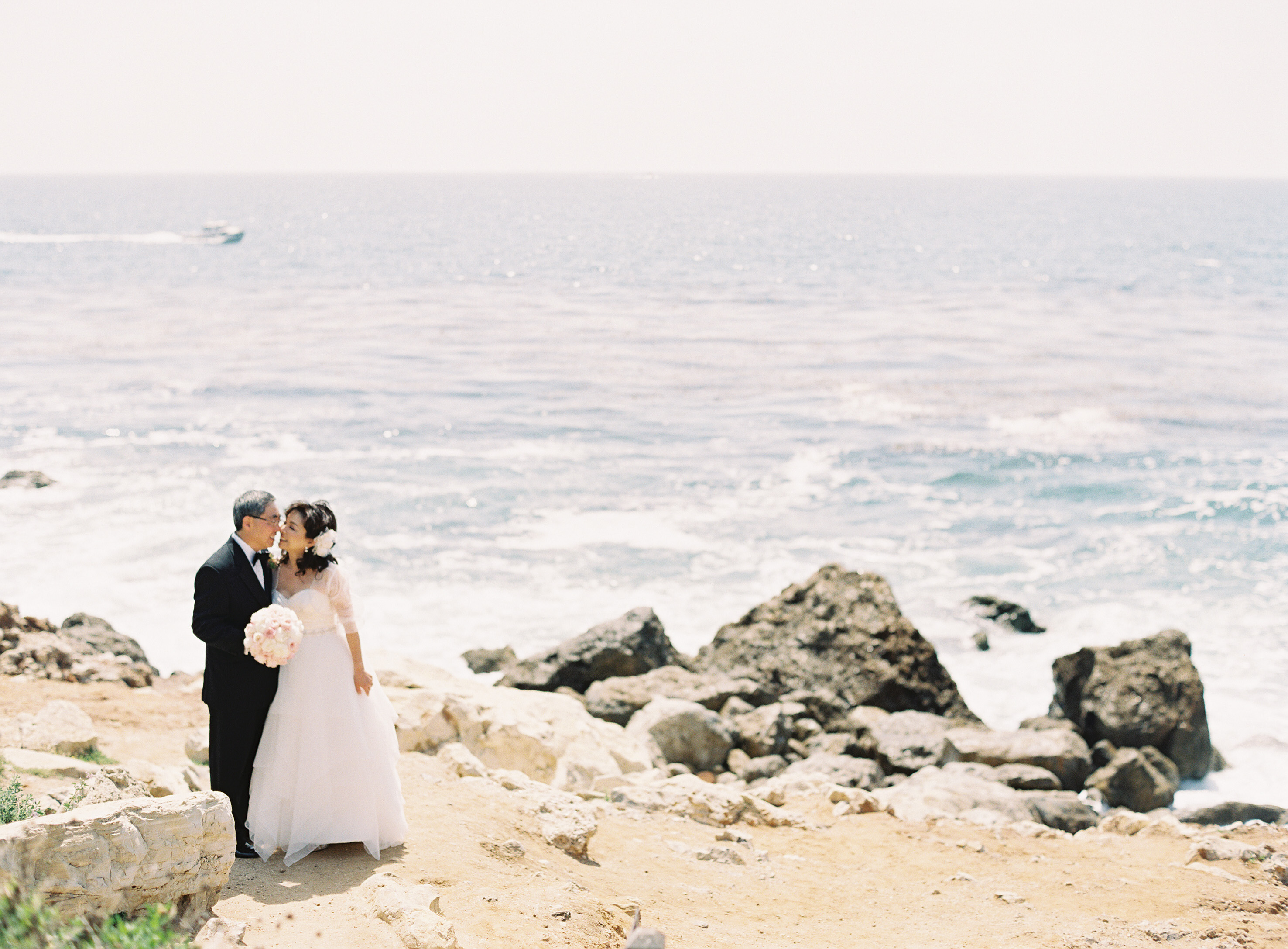Bride and groom standing on the bluffs with the ocean in the background
